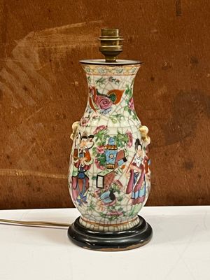 un vase muni d'une anse, posé sur une table sur laquelle se trouve une lampe