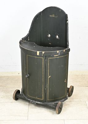 une armoire noire et dorée montée sur roulettes, posée sur un sol carrelé