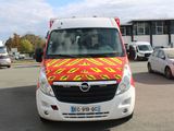 Des voitures sont garées sur un parking où se trouve une camionnette rouge et jaune