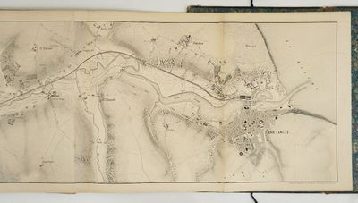 une vieille carte d'une ville posée sur une table, à côté d'un livre