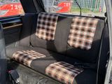 plaid seat covers in the back of a car with a red truck in the background