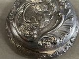 a small silver box with a floral design on it