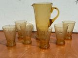 five glasses and a pitcher sitting on a table
