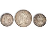 trois types différents de pièces d'argent sur une surface blanche