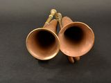 two brass trumpets sitting on a black surface