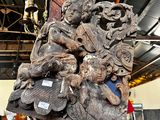 une grande sculpture en bois posée sur un socle dans un entrepôt