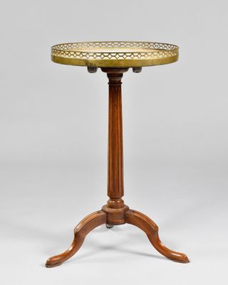 une petite table avec un plateau en laiton posé sur un piètement en bois