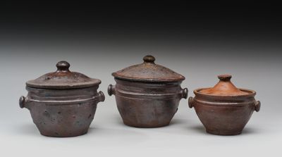 trois casseroles marron avec leurs couvercles sont posées sur une surface blanche