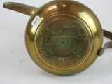 a gold tea pot with a handle on a white table
