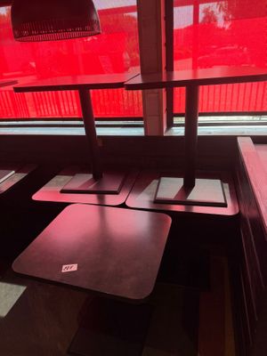des tables et des bancs dans un restaurant, avec une lumière rouge qui filtre à travers la fenêtre