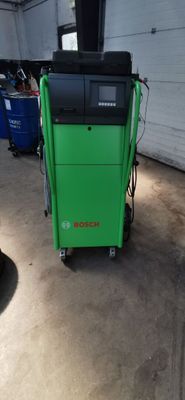 une photo d'une machine verte dans un garage, à côté d'une poubelle bleue