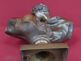 statue en bronze représentant un homme assis sur une caisse, sur fond rouge