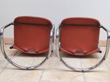 pair of red leather lounge chairs with chrome frame legs