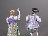three porcelain figurines of people dressed in costumes and hats