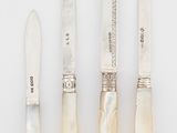 quatre pièces d'argenterie ornées de nacre sur un fond blanc