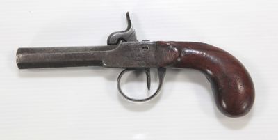 gros plan d'un pistolet avec un manche en bois sur une surface blanche