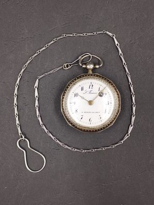 a pocket watch with a chain around it on a table
