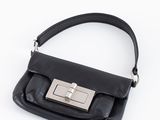 un sac à main noir muni d'un fermoir métallique sur fond blanc