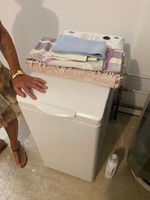 un homme debout à côté d'une machine à laver dans une pièce