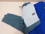 blue and grey nike tracksuits and a bag on a table