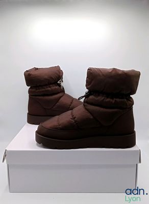 une paire de bottes d'hiver marron posée sur une boîte blanche