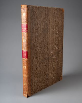 un vieux livre à la couverture rouge posé sur une surface grise