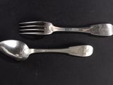 two spoons and a fork on a black table