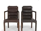 pair of brown leather chairs with arms and backrests