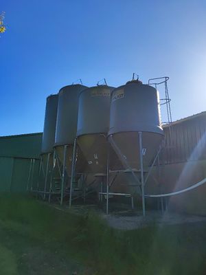 Le soleil brille de mille feux sur une ferme avec des silos au premier plan