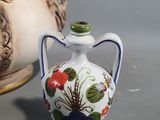 a white vase with a green lid and a blue and white vase with a bird on it