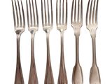 six forks are lined up in a row on a white surface