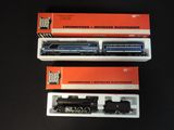 three boxed boxed model trains sitting on top of a black table