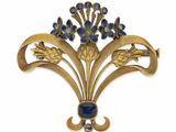 un gros plan sur une broche ornée de fleurs et de feuilles