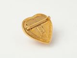 a close up of a gold heart shaped pin on a white surface
