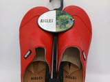 une paire de sabots en cuir rouge auxquels est fixé un parapluie
