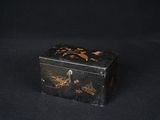 une vieille boîte noire et dorée posée sur une table noire