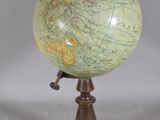 un globe antique posé sur un socle en bois, sur fond blanc