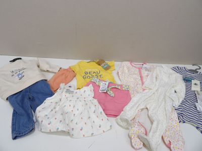 une pile de vêtements de bébé posée sur une table blanche