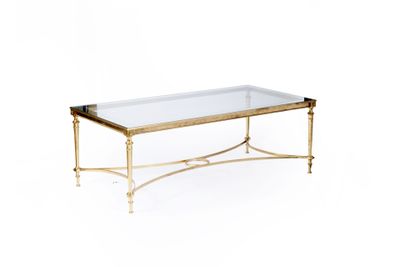 une table basse dorée avec un plateau en verre et des pieds en métal