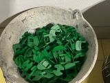 a bucket full of green plastic letters next to a bowl of green plastic letters