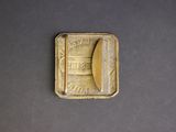 a small gold plate with a picture of a boat on it