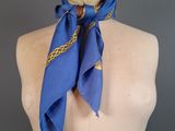a blue scarf with a gold design on it on a mannequin