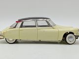 yellow toy car pulling a wooden stick across a white surface