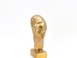 sculpture en or représentant la tête d'une femme, posée sur un socle en or
