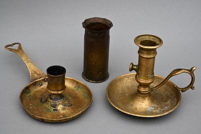 deux bougeoirs anciens en laiton et un candélabre posés sur une table