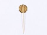 a gold coin on a toothpick on a white surface