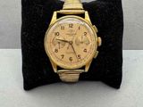 une photo d'une montre en or posée sur un coussin en velours noir