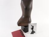 a sculpture of a female torso next to a book