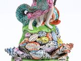 une figurine représentant une femme assise sur un tas de coquillages