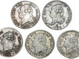 four silver coins of different sizes and shapes on a white background